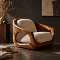 Corner detail of sculpted wooden lounge chair with open sides and cream seat and back cushions beside wood, brass and linen samples
