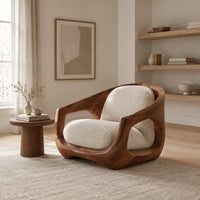 Sculpted wooden lounge chair with open sides and cream seat and back cushions in a Scandinavian living room with white walls