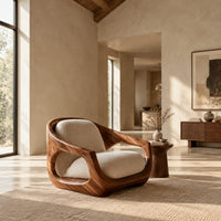 Sculpted wooden lounge chair with open sides and cream seat and back cushions in a bright open plan living room