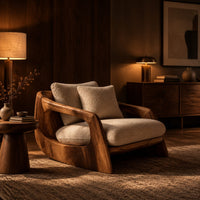 Lounge chair with a sculpted wood shell and thick cream cushions in an evening living room with walnut wall paneling
