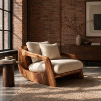 Lounge chair with a sculpted wood shell and thick cream cushions in an industrial loft living room with exposed brick