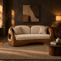 Carved wood shell sofa with oval arm openings and a cushioned seat in a dark living room at golden hour