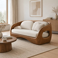 Carved wood shell sofa with oval arm openings and a cushioned seat in a Scandinavian living room with white walls