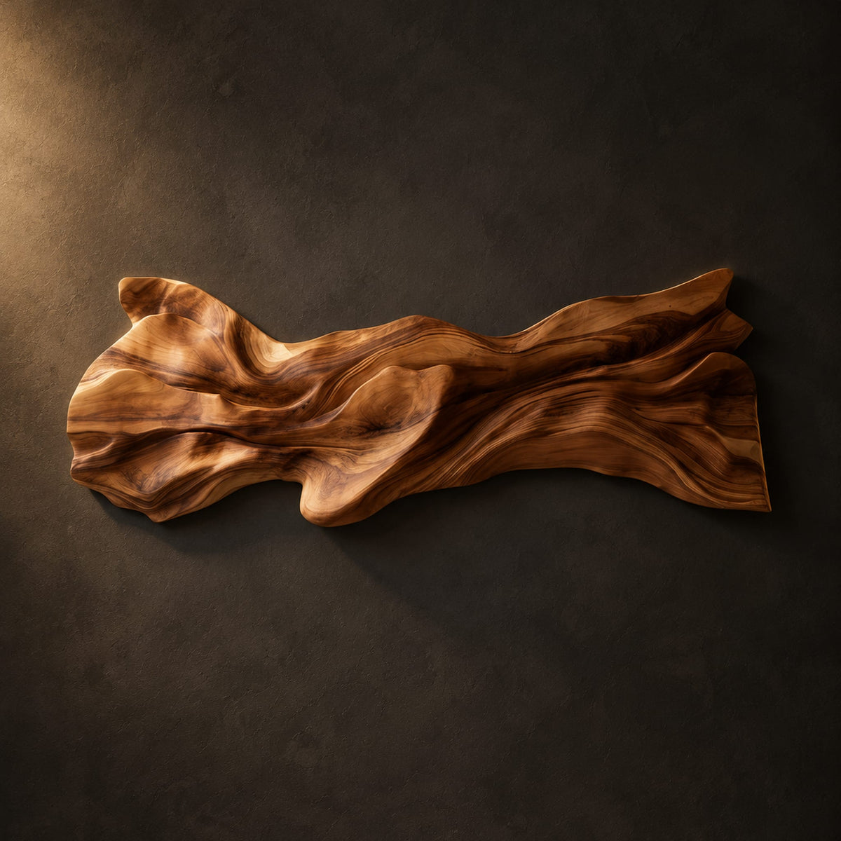 Long sculpted wood wall art with layered flowing folds and an uneven outline on a dark charcoal plaster wall