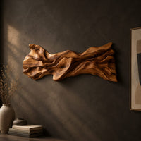 Long sculpted wood wall art with layered flowing folds and an uneven outline, three-quarter view showing the carved depth