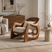 Sculptural wooden chair with looping arms and teardrop side openings in a Scandinavian living room with white walls