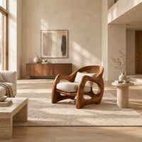 Sculptural wooden chair with looping arms and teardrop side openings in a bright open plan living room
