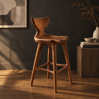 Bar stool with a winged backrest and a dished saddle seat, three-quarter view showing the grain