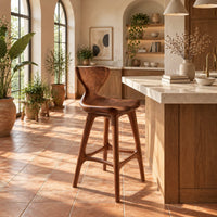 Bar stool with a winged backrest and a dished saddle seat in a bright kitchen with arched windows and plants