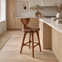 Bar stool with a winged backrest and a dished saddle seat in a Scandinavian kitchen with white walls