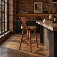 Bar stool with a winged backrest and a dished saddle seat in an industrial loft kitchen with exposed brick