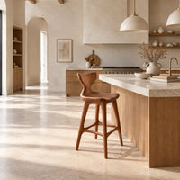 Bar stool with a winged backrest and a dished saddle seat in a bright open plan kitchen