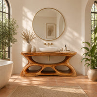 Vanity with a flowing oval top and a sculpted base pierced by smooth openings in a bright bathroom with arched windows and plants