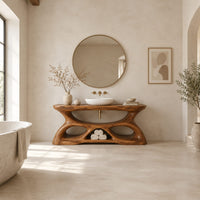 Vanity with a flowing oval top and a sculpted base pierced by smooth openings in a bright open plan bathroom