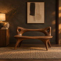 Bench with an open loop backrest and four splayed legs in a dark entryway at golden hour