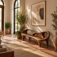Wooden bench with a low backrest cut with two oval openings on tapered legs in a bright entryway with arched windows and plants