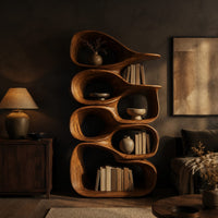 Tall bookshelf made of stacked open wooden cells with a pointed top in a dark living room at golden hour