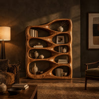 Bookshelf with staggered teardrop openings and sloped top in a dark living room at golden hour