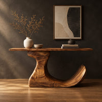 Console table on an off center pedestal with curled foot in a dark studio against a charcoal plaster wall