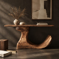 Corner detail of console table on an off center pedestal with curled foot beside wood, brass and linen samples