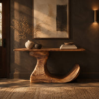 Console table on an off center pedestal with curled foot in a dark entryway at golden hour