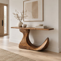 Console table on an off center pedestal with curled foot in a Scandinavian entryway with white walls