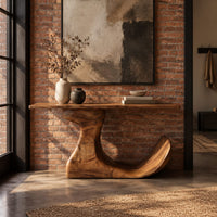 Console table on an off center pedestal with curled foot in an industrial loft entryway with exposed brick