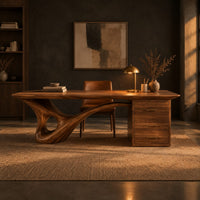 Sculptural desk with a looping wave leg and a three drawer pedestal in a dark home office at golden hour