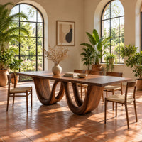 Rectangular dining table on a wavy ribbon base in a bright dining room with arched windows and plants