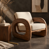 Corner detail of lounge chair with thick open loop arms and sled base beside wood, brass and linen samples