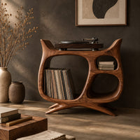 Corner detail of sculptural record player stand with a large open bay, oval openings and splayed feet beside wood, brass and linen samples