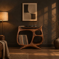 Sculptural record player stand with a large open bay, oval openings and splayed feet in a dark living room at golden hour