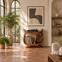 Sculptural record player stand with a large open bay, oval openings and splayed feet in a bright living room with arched windows and plants