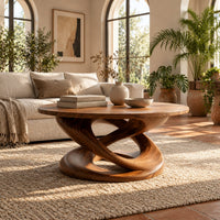 Round coffee table on a twisting interlaced loop base in a bright living room with arched windows and plants
