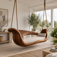 Boat shaped wooden swing with scrolled ends and a long seat cushion in a Scandinavian porch with white walls