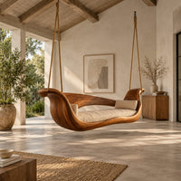 Boat shaped wooden swing with scrolled ends and a long seat cushion in a bright open plan porch