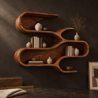 Corner detail of sculptural wall shelf with three winding open tiers beside wood, brass and linen samples