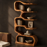 Corner detail of tall serpentine bookshelf with staggered slab shelves and a loop base beside wood, brass and linen samples
