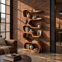 Tall serpentine bookshelf with staggered slab shelves and a loop base in an industrial loft living room with exposed brick