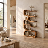 Tall serpentine bookshelf with staggered slab shelves and a loop base in a bright open plan living room