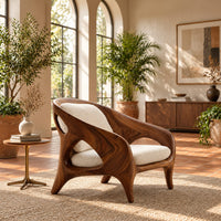 Shell back chair with oval side openings and splayed legs in a bright living room with arched windows and plants