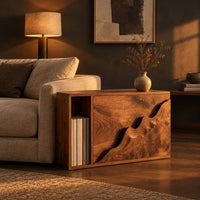Boxy wood side table with a carved wave front panel and an open slot in a dark living room at golden hour
