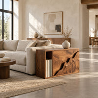 Boxy wood side table with a carved wave front panel and an open slot in a bright open plan living room