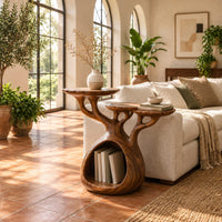Tree form wood side table with three tops and a hollow base in a bright living room with arched windows and plants