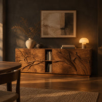Low sideboard with carved branch doors and an open center bay in a dark dining room at golden hour