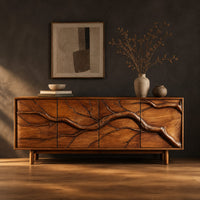 Low sideboard with a carved branch pattern across four front panels in a dark studio against a charcoal plaster wall