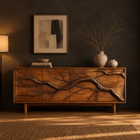 Low sideboard with a carved branch pattern across four front panels in a dark dining room at golden hour