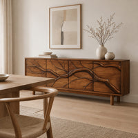Low sideboard with a carved branch pattern across four front panels in a Scandinavian dining room with white walls