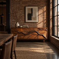 Low sideboard with a carved branch pattern across four front panels in an industrial loft dining room with exposed brick