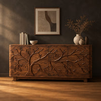 Sideboard with a carved branching tree relief across four front panels in a dark studio against a charcoal plaster wall